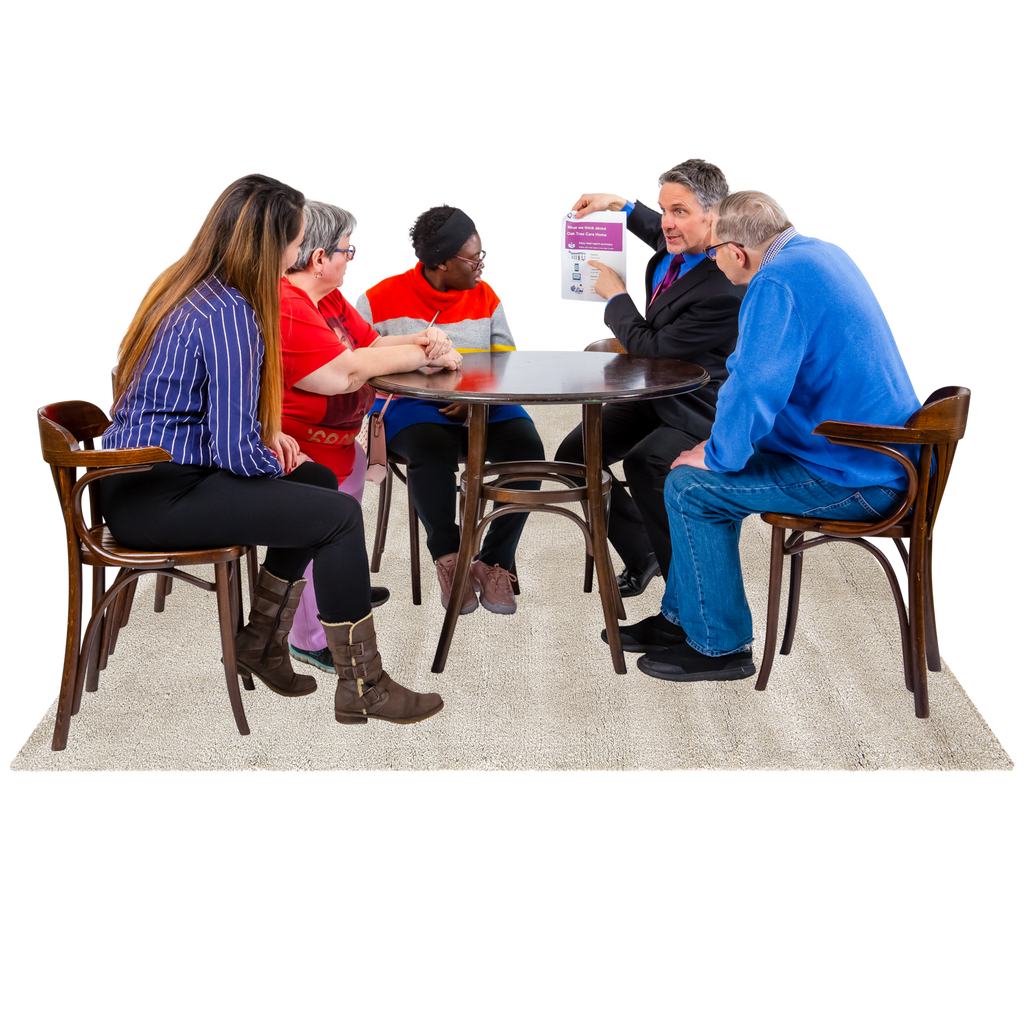 Five people sit at a table discussing an Easy Read document.